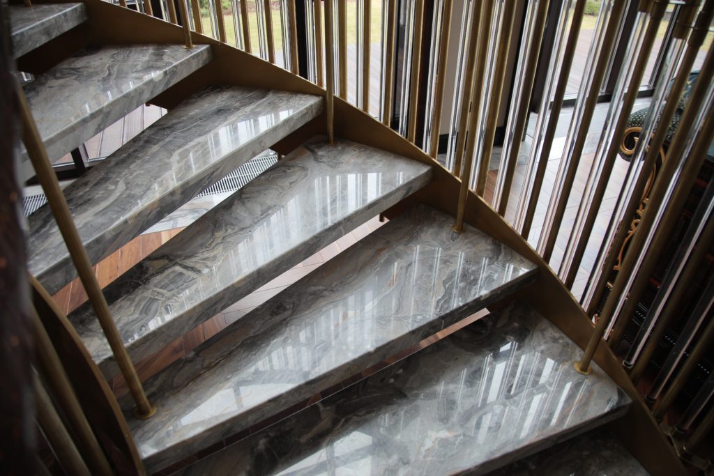 Воздушная, винтовая лестница с ограждением из латуни и стекла.