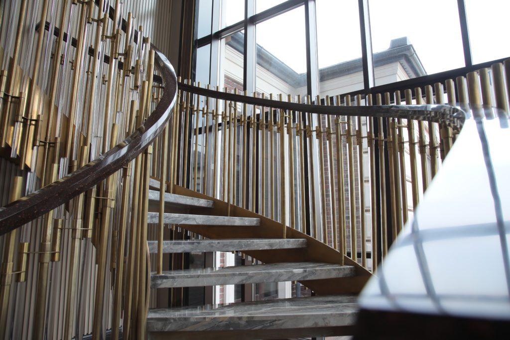 Винтовая лестница с ограждением из латуни и стекла